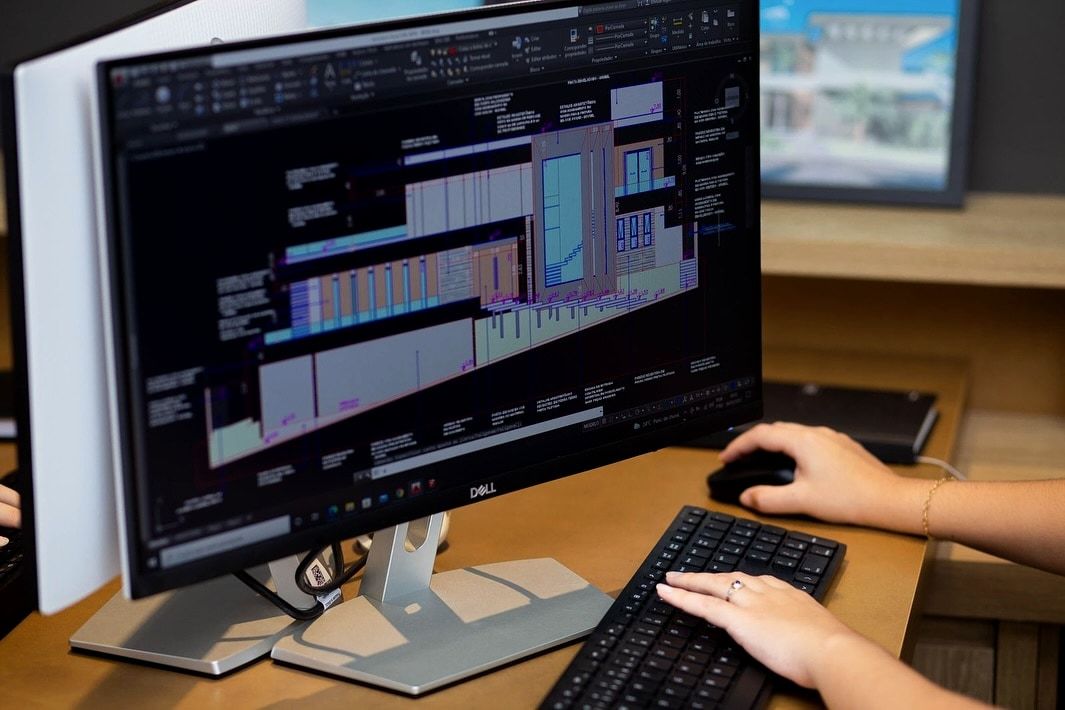Fotografia de detalhamento em AutoCAD na tela do escritório, com elevações e cotas.